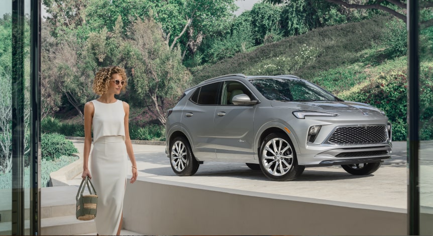 An OnStar-subscribed Buick SUV parked at a driveway as a person passes by.