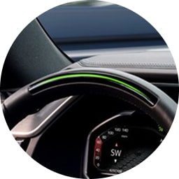 Steering wheel with illuminated green light bar indicating Super Cruise is active.