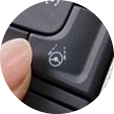 Close-up of a driver pressing the Super Cruise hands-free driving activation button.