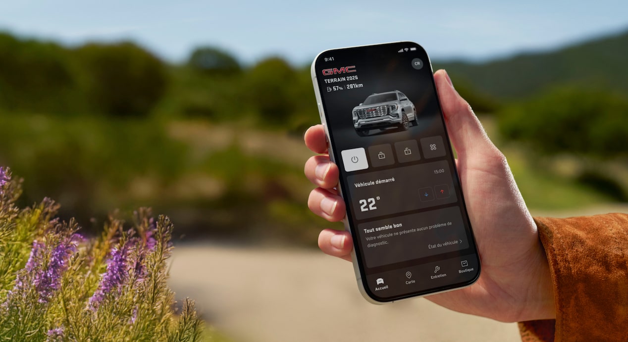 La main droite d'une personne tenant un téléphone intelligent qui affiche l'application OnStar Guardian.