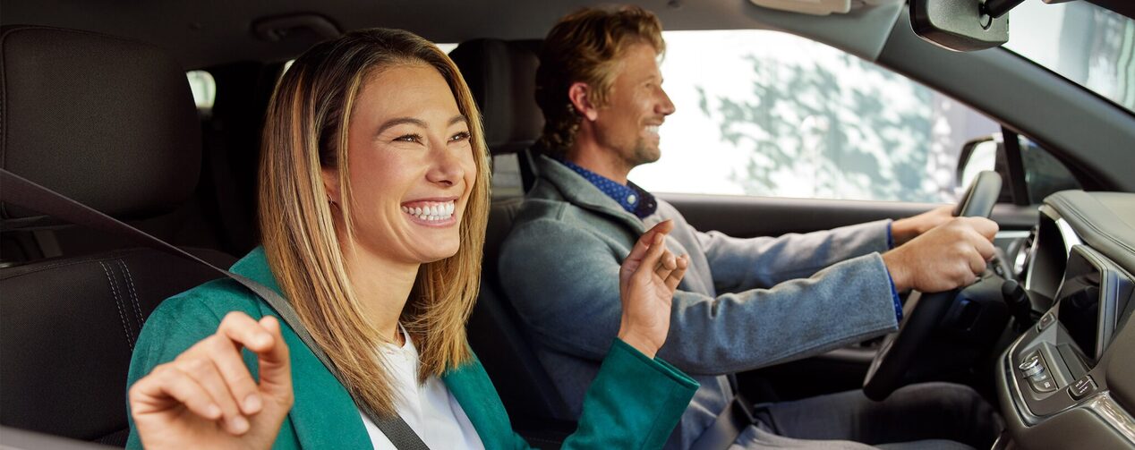 Two people smiling inside a vehicle.