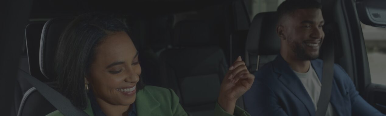Deux personnes heureuses assises à l’avant d’un véhicule abonné à OnStar.