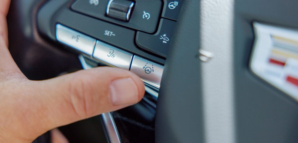  A person's hand touching a button on the steering wheel.