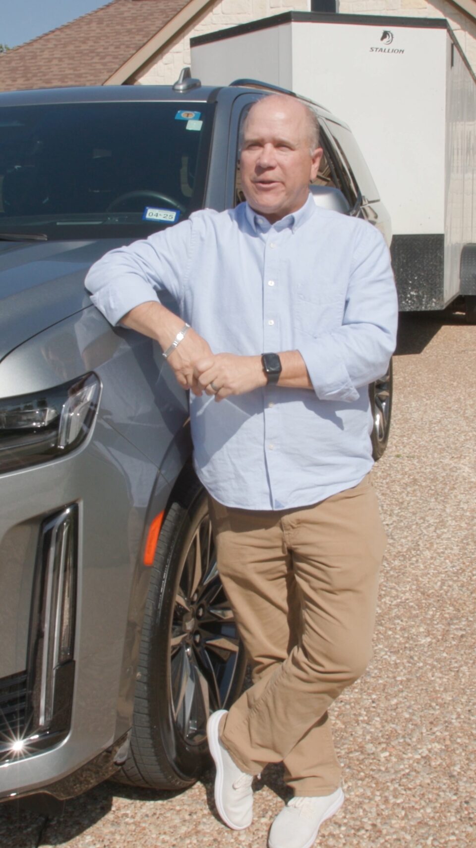 A close up image of Eric standing next to his Cadillac with his arm on the left side of the hood.