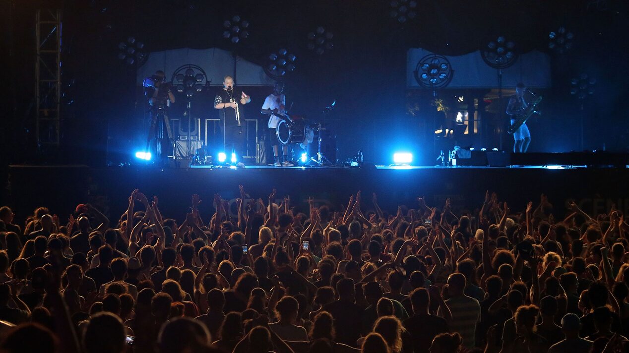A crowd enjoying the music of a rock band outdoors thanks to OnStar's safety services.