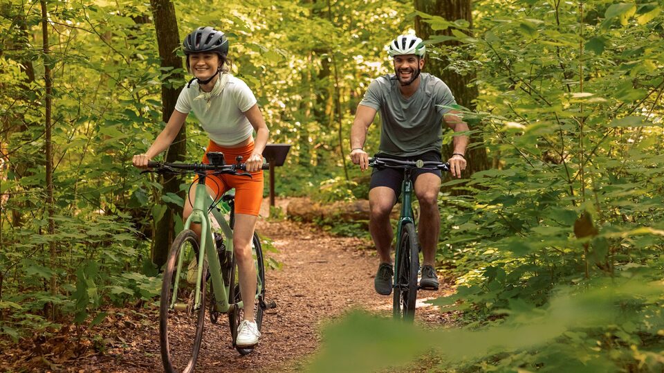 Two people happily biking in a forest thanks to OnStar's safety services.