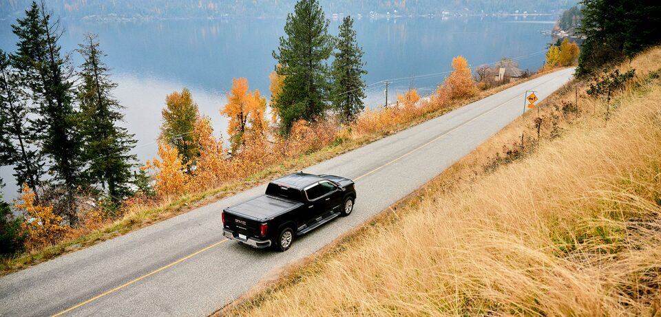 GMC Sierra 1500 pickup truck driving on a road with a deer warning sign.