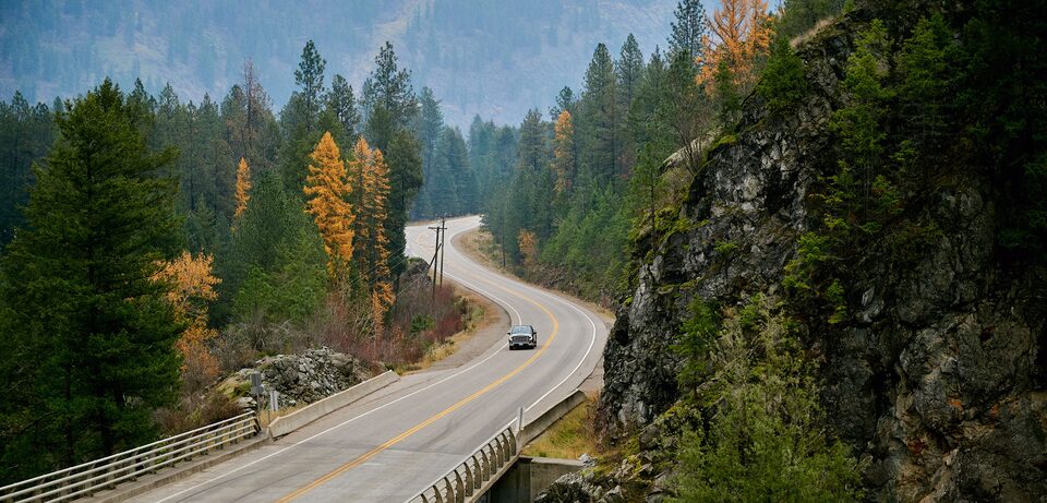Scenic view of a GMC Sierra 1500 pickup truck driving on a road.