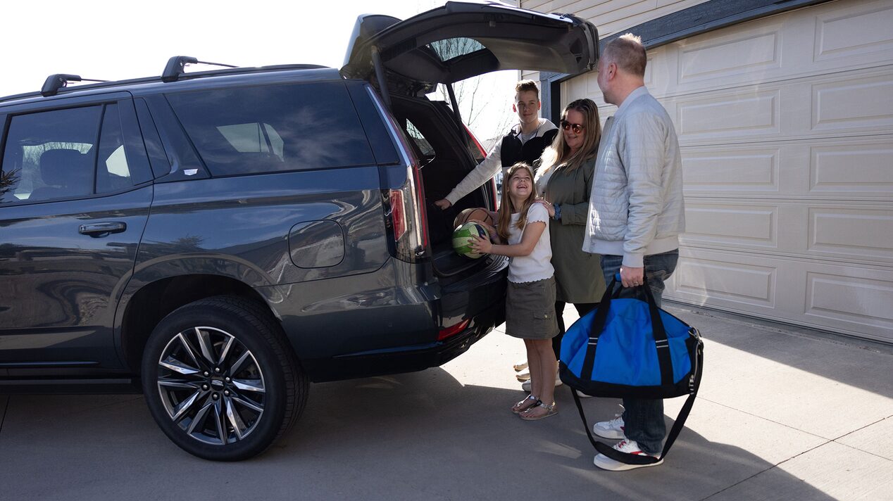 OnStar member Justin VanDyk and his family loading their things in the trunk of a Cadillac SUV.