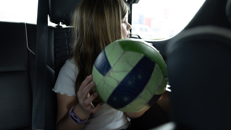 OnStar member Justin VanDyk's daughter seated inside their Cadillac SUV while holding a volleyball.