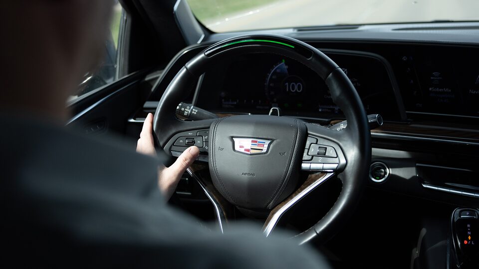 OnStar member Justin VanDyk holding the steering wheel while inside his Cadillac SUV.