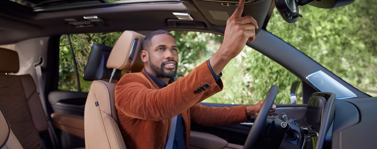 Man in Drivers Seat Reaching for OnStar Blue Button