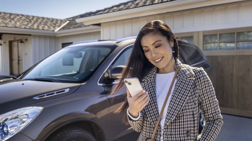 Femme utilisant l’application Onstar Guardian à l’extérieur de sa maison.