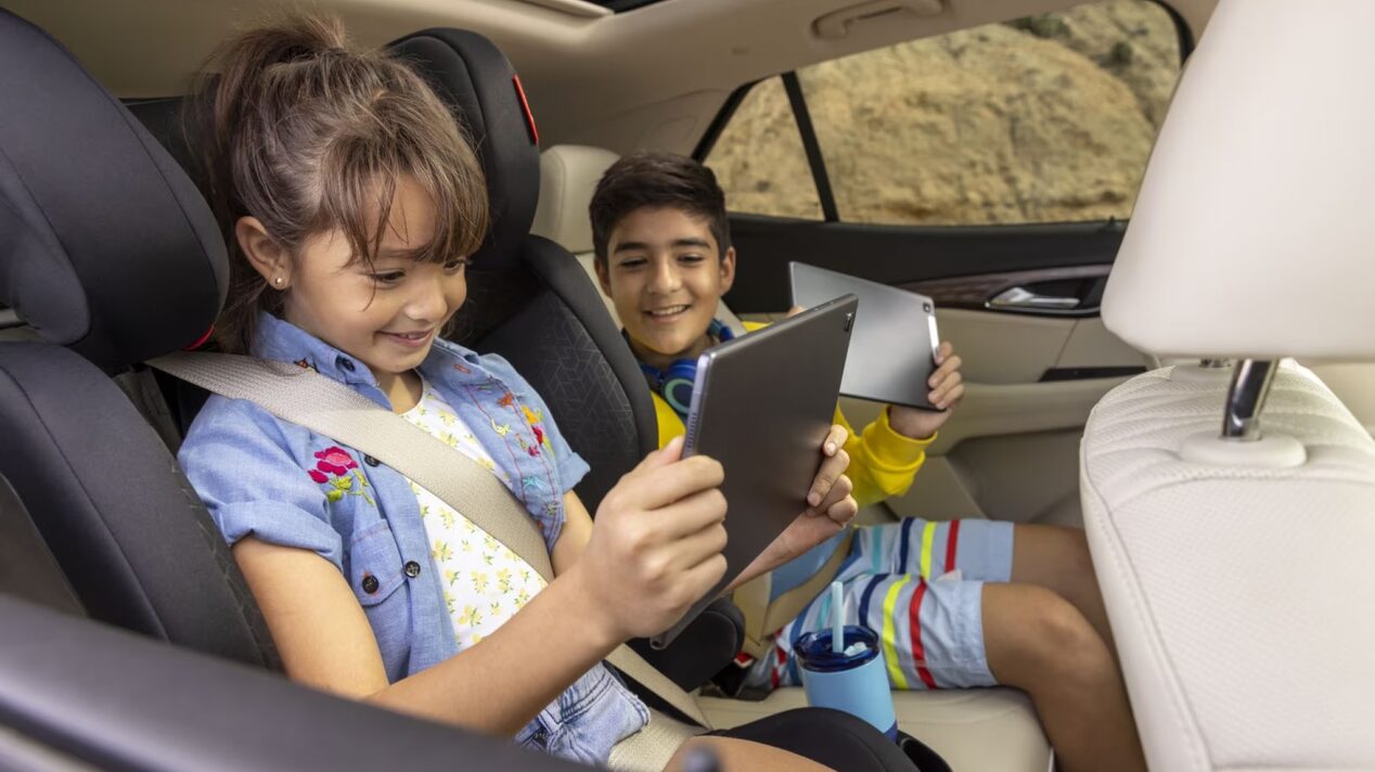 Kids using gadgets in a vehicle.