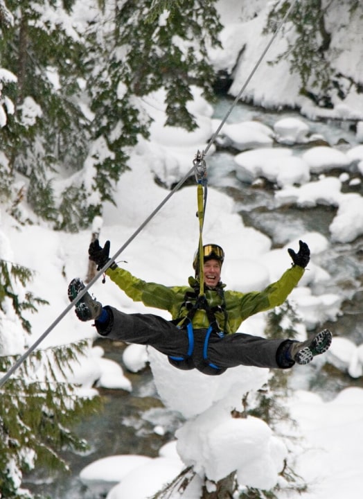 A person zip lining alone on a snowy environment.