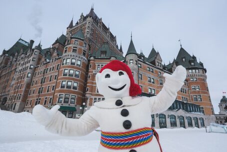 Une mascotte en forme de bonhomme de neige pose pour la caméra devant un château.