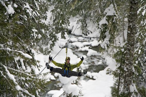 A person zip lining alone on a snowy environment.