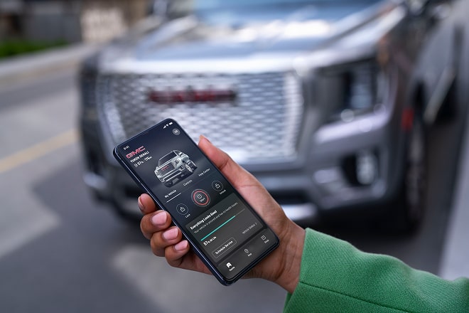 Une personne accède à une fonctionnalité OnStar depuis son téléphone intelligent à l’extérieur d’un véhicule GMC.