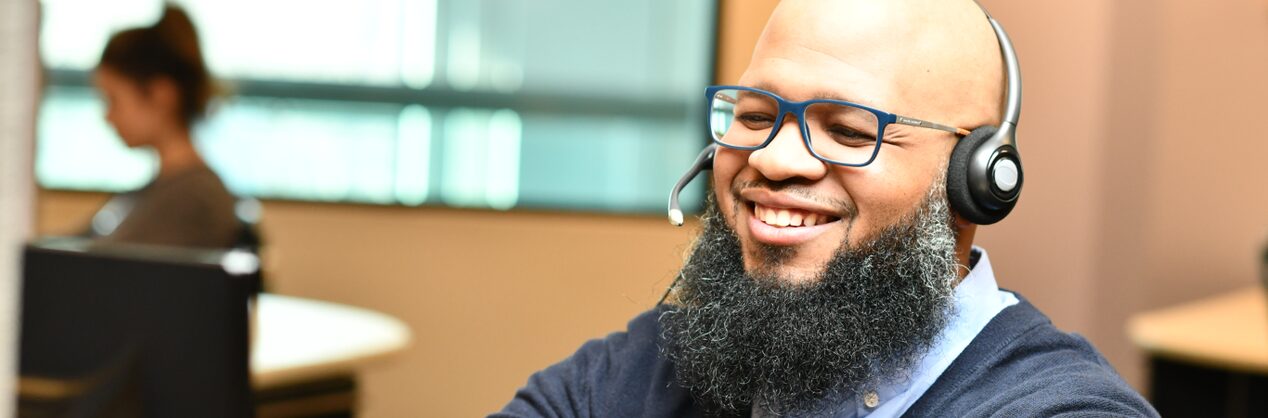 A male OnStar advisor smiling while wearing a headset.