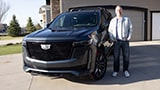 OnStar member Justin VanDyk smiling while standing next to his Cadillac Escalade SUV.